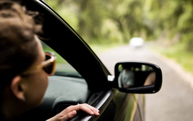 Young woman riding with head out car window